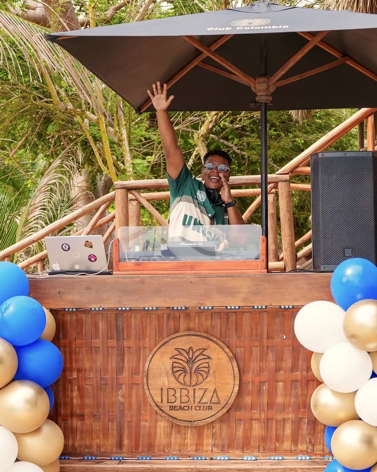 DJ mezclando en la cabina de madera de Ibbiza Island Beach Club bajo las palmeras