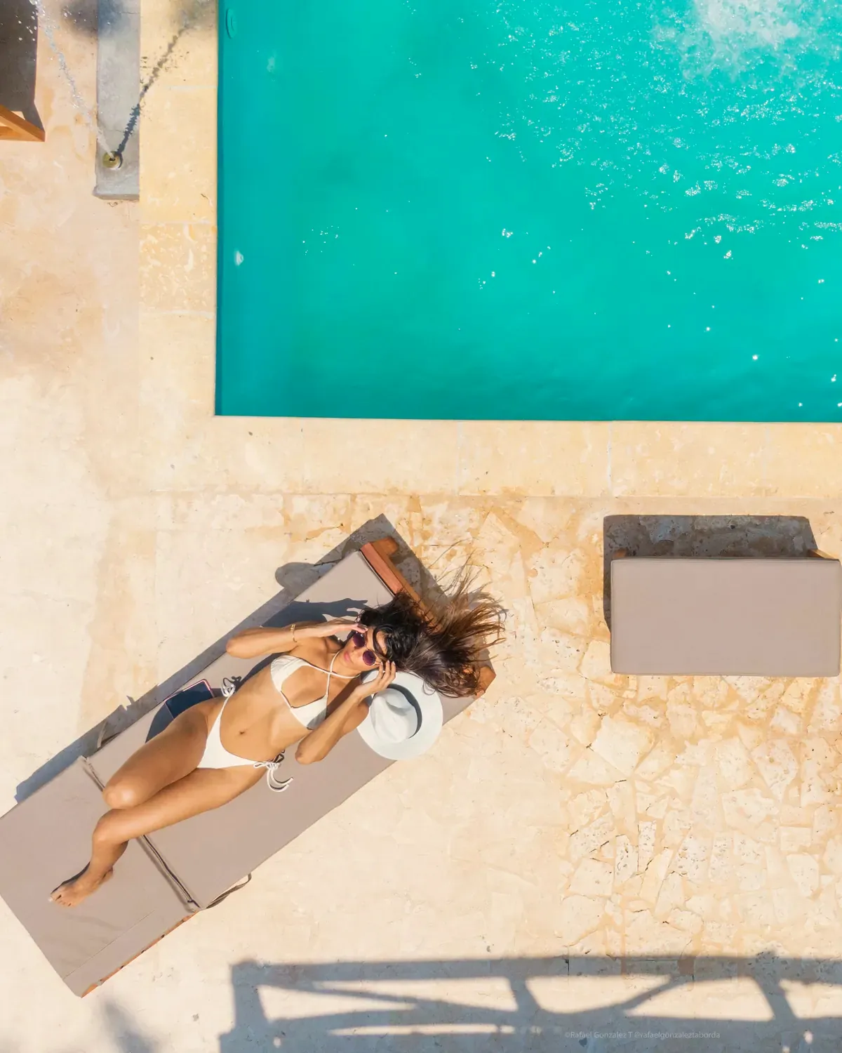 Vista aérea de una bañista tomando el sol junto a la piscina turquesa de Ibbiza